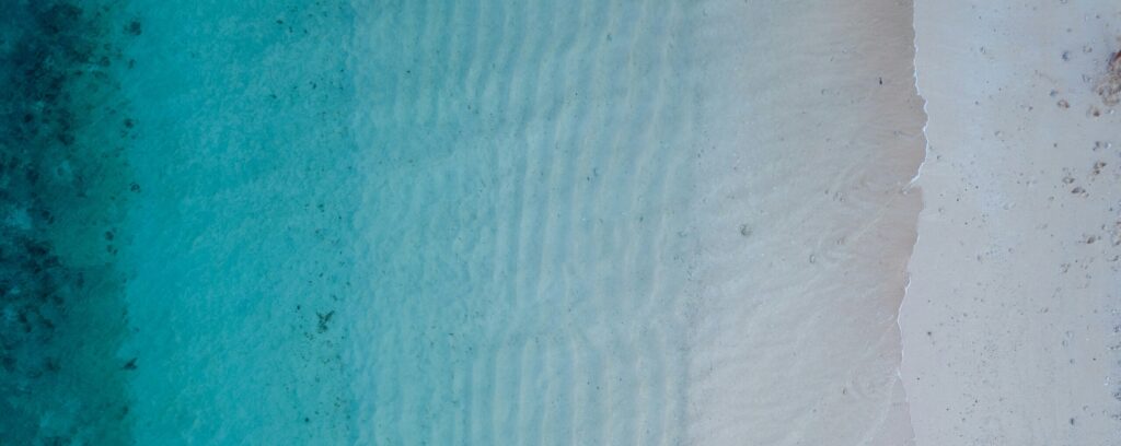 an overhead shot of a beach where the dark waters gradually become lighter as they transition to the sand, reflecting the measured progress of brand transition strategy